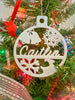 A white circular christmas tree ornament in a tree that says caitlin and has bells, snow flakes and a deer.