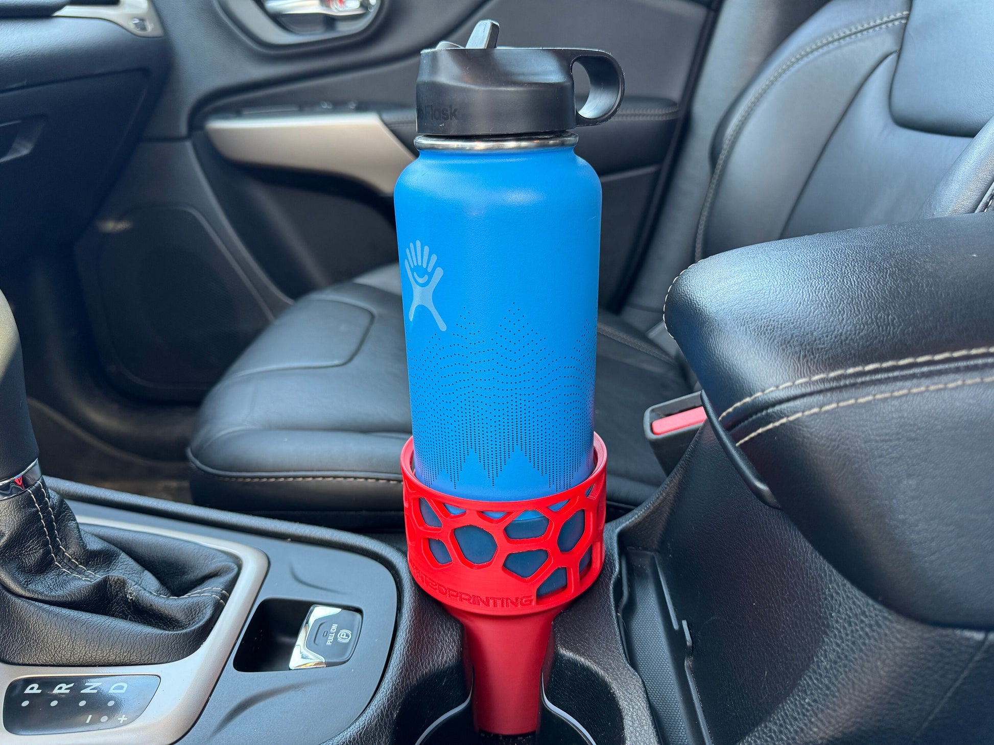 A red car cup holder adapter holding a 32 oz hydro flask water bottle