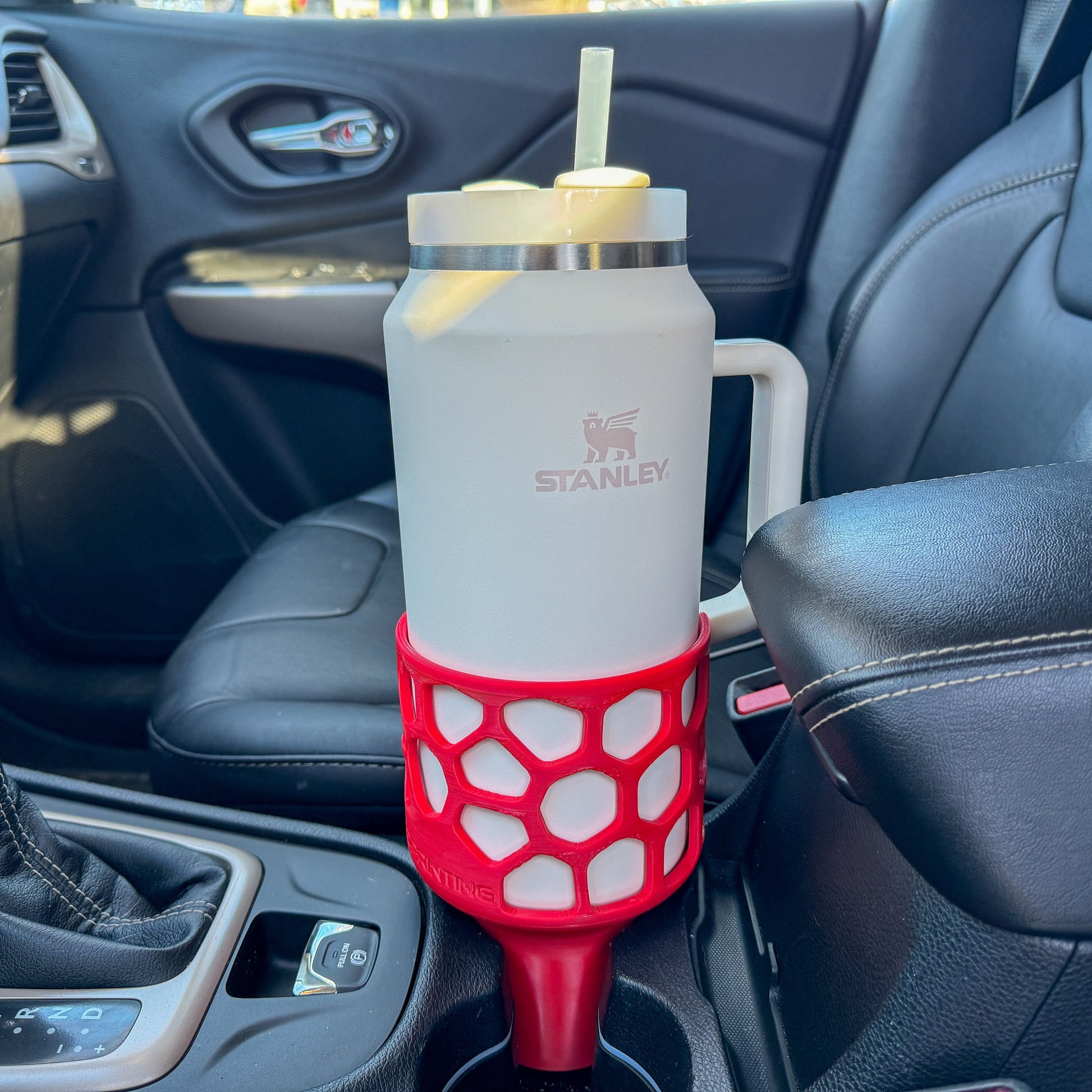 A red car cup holder adapter holding a 64 oz yeti tumbler water mug in a car