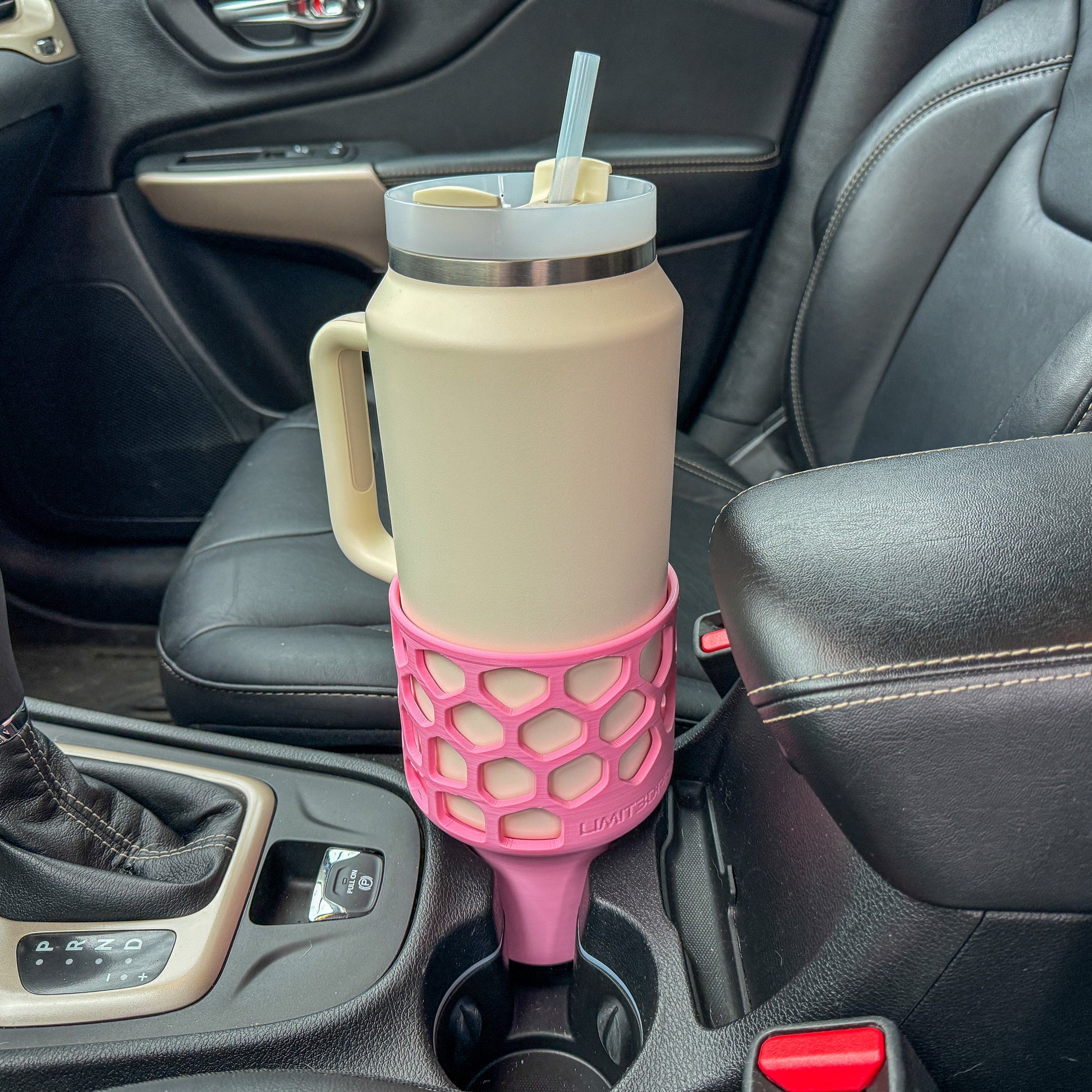 A pink car cup holder adapter holding a 64 oz yeti tumbler water mug in a car