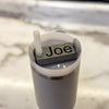 A gray name plate with black lettering that says Joe on top of a 20 or 30oz stanley tumbler