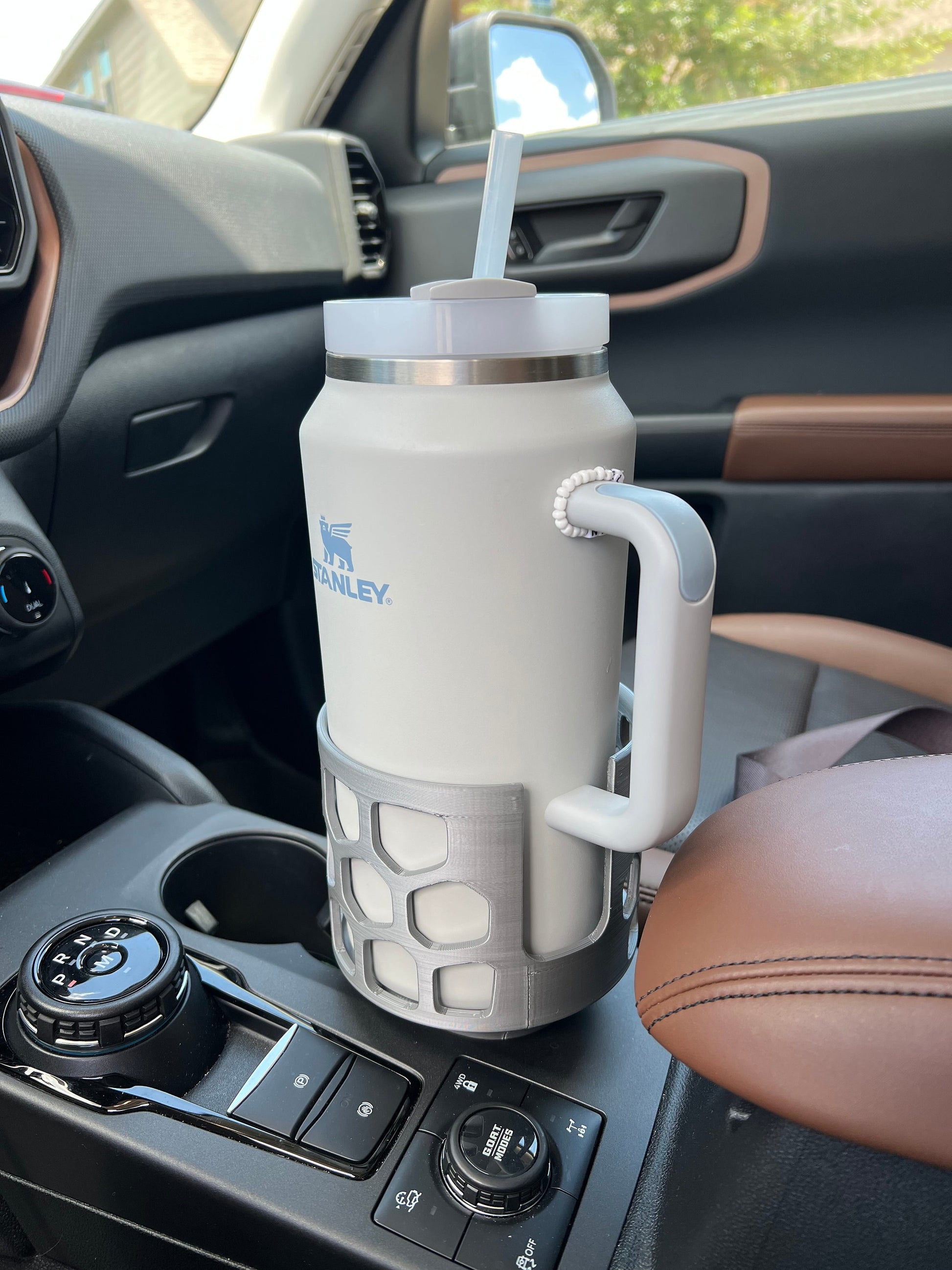 A grey car cup holder adapter holding a 64 oz yeti tumbler water mug in a car