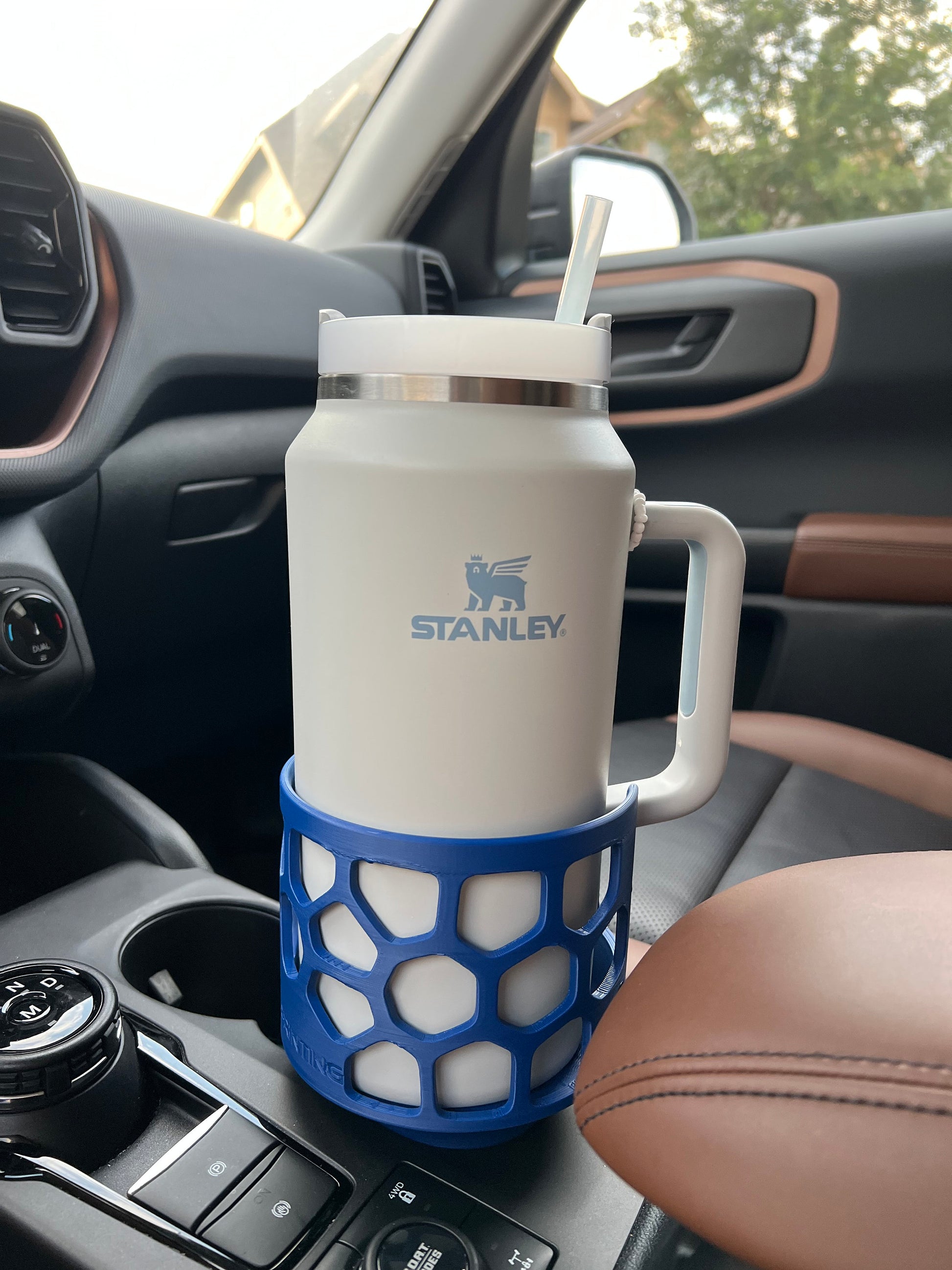 A blue car cup holder adapter holding a 64 oz yeti tumbler water mug in a car