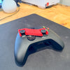 A black xbox controller on a desk with the xbox controller stick holder on the controller to show how the holder works.